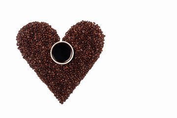 a handful of heart-shaped coffee beans with a Cup of coffee in the middle. a Cup of black coffee on the background of a coffee heart. Coffee abstraction in the shape of a heart on a white background