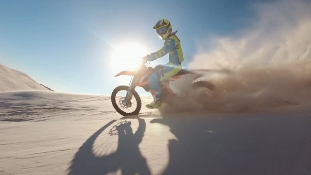 Skilled motocross rider drives on the sand dune. Dirt biker off roading on sand dunes in desert.
