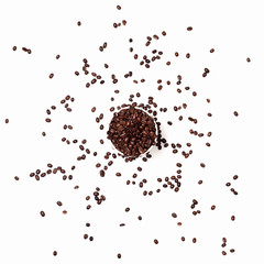 coffee background of scattered coffee beans. fried brown coffee beans in a glass in the center of the frame along with a handful of scattered beans on the surface. coffee abstraction, white background