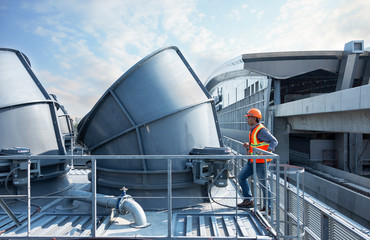 worker standing  top of cooling tower on blue sky background