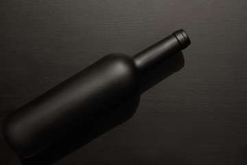 wine bottle black matte laying on black background, table, top view, copy space 