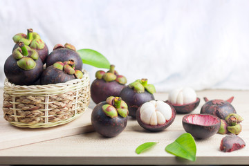 Mangosteen and cross section showing the thick purple skin and white flesh of the queen of friuts, Delicious mangosteen fruit arranged on a bowl, Mangosteen flesh, closeup. Mangosteen.