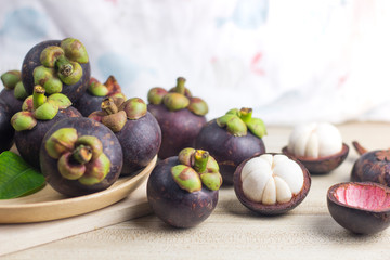 Mangosteen and cross section showing the thick purple skin and white flesh of the queen of friuts, Delicious mangosteen fruit arranged on a bowl, Mangosteen flesh, closeup. Mangosteen.