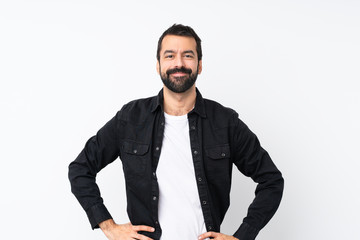 Young man with beard over isolated white background posing with arms at hip and smiling