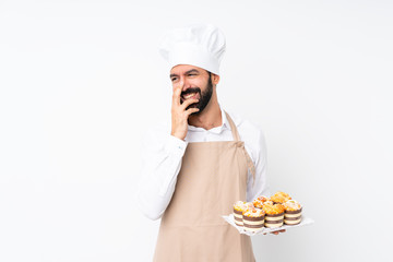 Young man holding muffin cake over isolated white background smiling a lot