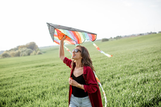 Portrait of a young and carefree woman launching kite on the greenfield. Concept of active lifestyle in nature