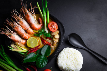 Tom Yum Kung or Tom Yum Goong Spicy Sour Soup  Thai local food, and with vegetable ingredients is an image element on black concrete cement background top view, with copy space to place text