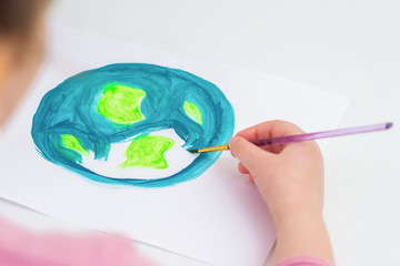 Child draws planet for earth day. Protection of environment. Earth Day celebration. Save world and unity concept.