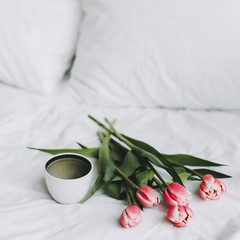 Coffee cup and tulips in bed. Concept of holiday, birthday, Women Day. Breakfast in bed. Good morning. still life, flat lay