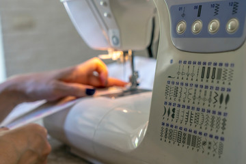 close-up of the seamstress's hands at the sewing machine hem fabric, clothing