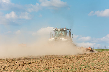 In the spring, a farmer pulls harrows with a modern tractor and sows a field with beets. Sowing...