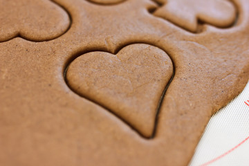 Christmas joy of cutting out cookies out of gingerbread dough, with a variety of decorative cutters. Cookies in shape of heart.