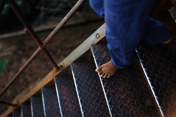 Barefoot on the metal ladder comes down a child 