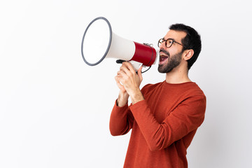 Caucasian handsome man with beard over isolated white background shouting through a megaphone - obrazy, fototapety, plakaty