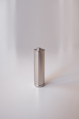 A gray AA model battery stands upright on a white background