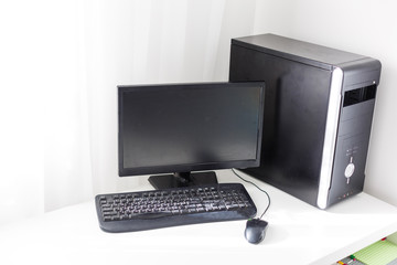 black computer with monitor are on the table at home