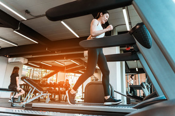 Fototapeta na wymiar young sports woman is running treadmill in gym. Doing cardio training 