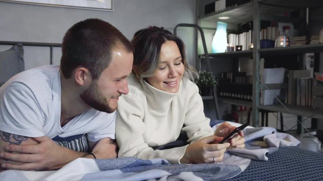 Couple lying in bed with mobile phones in hands