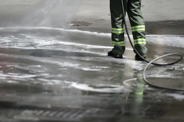 Public janitor deep cleaning the sidewalk and cycling lane with high pressure disinfectant solution...