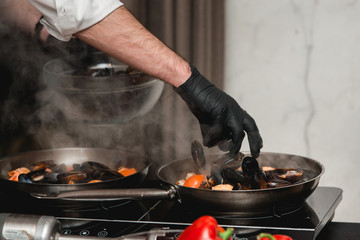 Chief in a restaurant cooking seafood with sauce