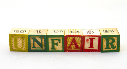 The term unfair displayed visually on a clear background using colored wooden toy blocks image in...