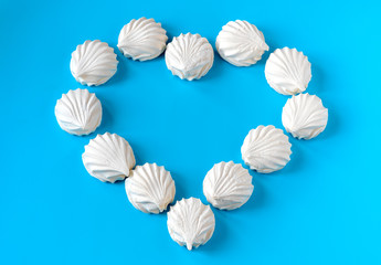 white vanilla marshmallows laid out on a blue background in the form of hearts. breakfast for a loved one. wedding concept