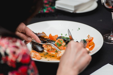Woman in a restaurant eating seafood with sauce