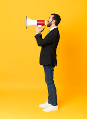 Full-length shot of business man over isolated yellow background shouting through a megaphone