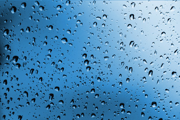 Rainy blue background, rain water drops on the window or in shower stall, season backdrop, abstract textured wallpaper