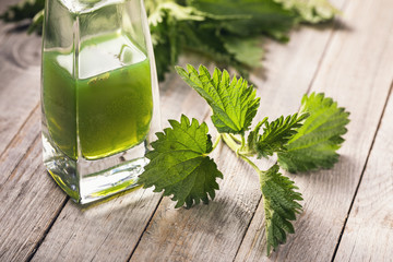 Alcohol tincture of nettle leaves on a wooden table, close-up. Medicinal herbs concept