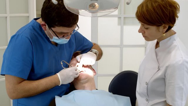 Dental clinic. Doctor dentist treats teeth to the patient in the dental clinic. Dentistry and orthodontist. Dental treatment and bite correction.