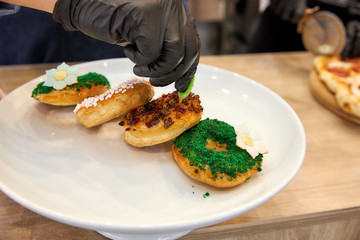 four round profiteroles cakes with colorful sprinkles on a white dish