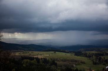 Obraz premium Black Rainy Clouds Cover The Forest And Grass Field