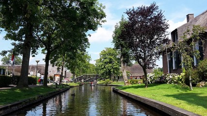 Fototapeta na wymiar View of famous typical Dutch village Giethoorn, called the Venice of the Netherlands or Venice of the North, with waterways, narrow walking paths, traditional houses and wooden bridges.