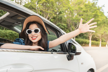 woman wearing sunglasses waving from the car window happily