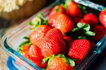 
Glass container full of precious fresh strawberries in the home kitchen. Low calorie healthy food, like fruit. Close up.