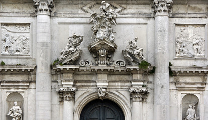 Photo of baroque marble facade in Venice with sculptures, columns, capitals, reliefs in historical part of Venice.