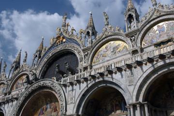Marble facade of St. Mark's Cathedral with mosaics, sculptures in Venice in sunny summer day.