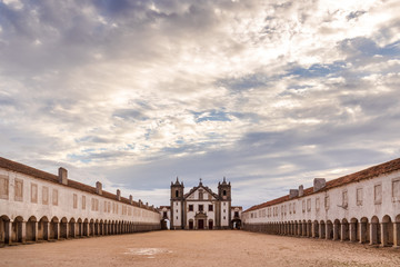The Nossa Senhora do Cabo church, located in Espichel Cape, Sesimbra in the Setubal peninsula, with its archs leading to the main building, on a cloudy day with the sun shining through the clouds