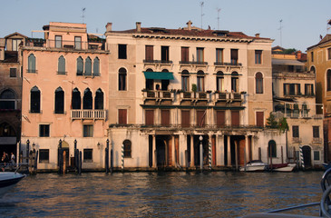 Fototapeta na wymiar Photo of Grand canal in Venice with historical facades made in baroque and renaissance styles with balustrades, piles, boats in sunny summer day.