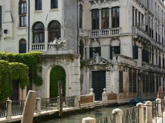 Naklejka premium Photo of canal in Venice with historical facades with balustrades, greenery, piles, boat.