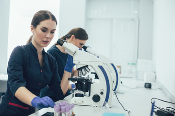 Two young females working with microscopes in the laboratory
