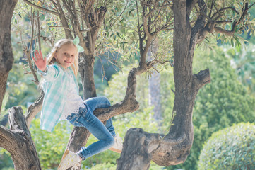 Happy girl sitting in a tree and enjoying the view. Summer time fun