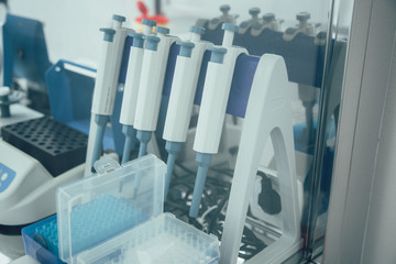 Several manual pipettes on the stand near lab equipment