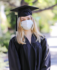 Blond woman in cap and gown wearing a mask for protection against covid-19 for the class of 2020.