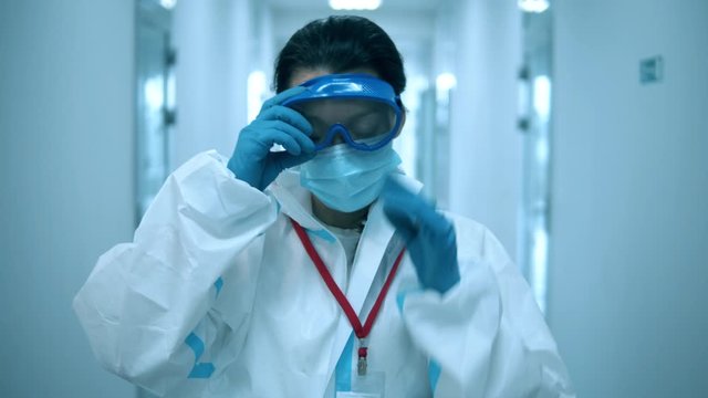 Female doctor takes off face mask after a working day at clinic.