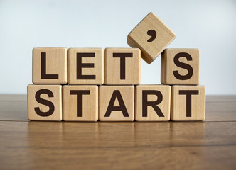 Concept word 'lets start' on cubes on a beautiful wooden background.