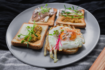 Variety of sandwiches for breakfast, snack, appetizers with fried egg, peanut paste, pea microgreen. Flat lay, top view