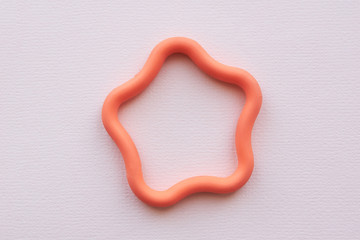Orange toy rubber star in the center of the frame on a pink background. Flat lay. Copy space.