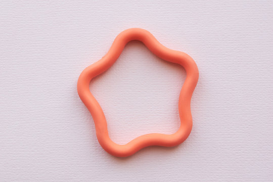 Orange toy rubber star in the center of the frame on a pink background. Flat lay. Copy space.